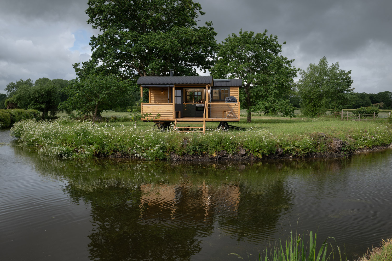 A handcrafted Blackdown shepherd hut set in a garden with a fire bowl and flowers